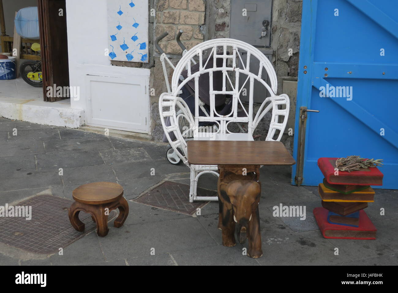 Interessante la tabella con elefante in legno e sedie su un marciapiede in piccolo insediamento su Panarea, illands Eolie, Italia. Foto Stock