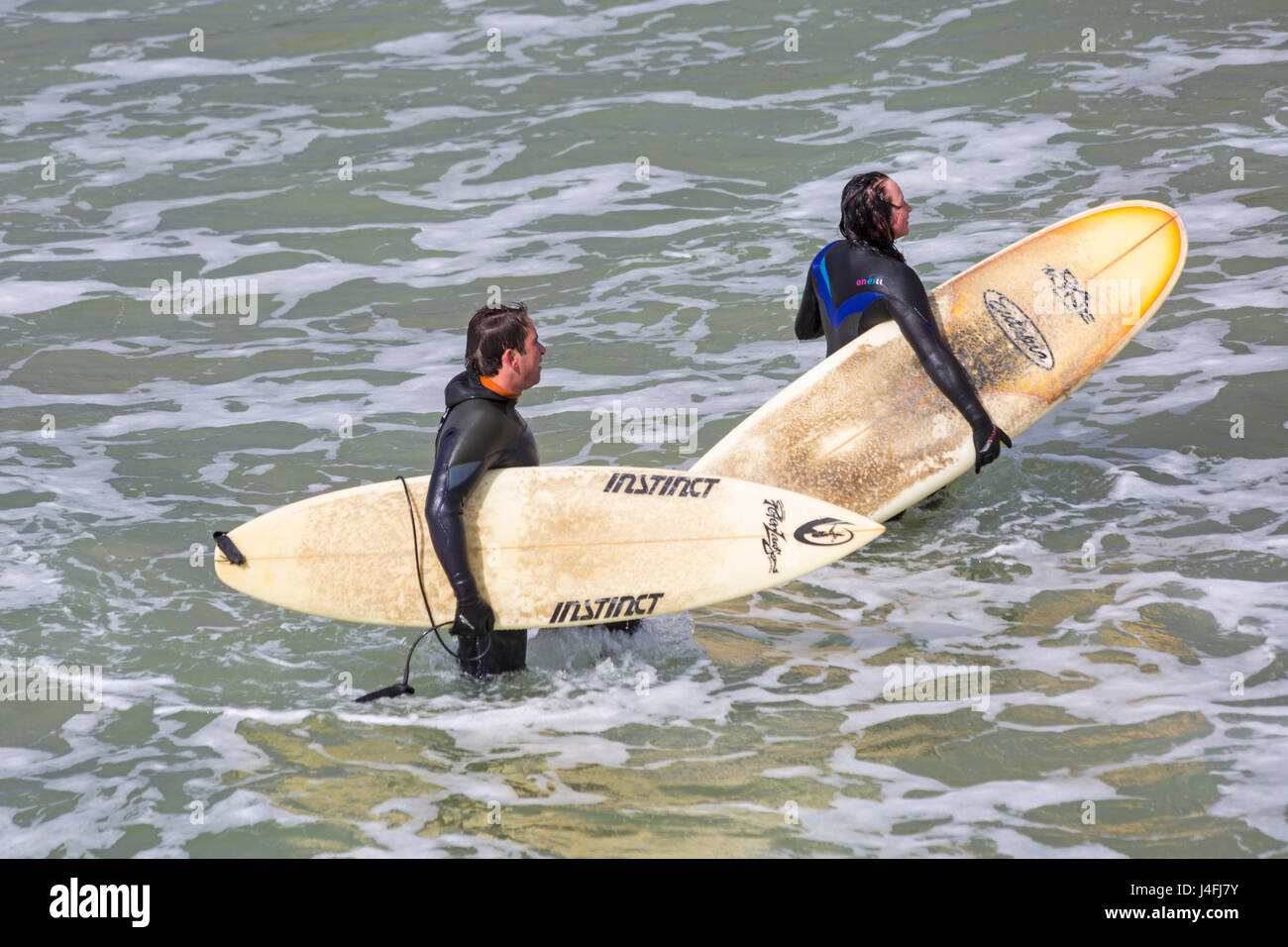 Surfers mantenendo le loro tavole da surf in mare dopo una buona sessione di navigazione su una bella giornata di sole a Bournemouth Beach su lunedì festivo nel Maggio Foto Stock