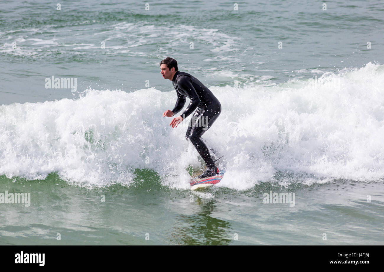 Surfer cavalcare un onda godendo il surf su una bella giornata di sole a Bournemouth Beach su lunedì festivo nel maggio - Bournemouth Dorset, Regno Unito Inghilterra Foto Stock