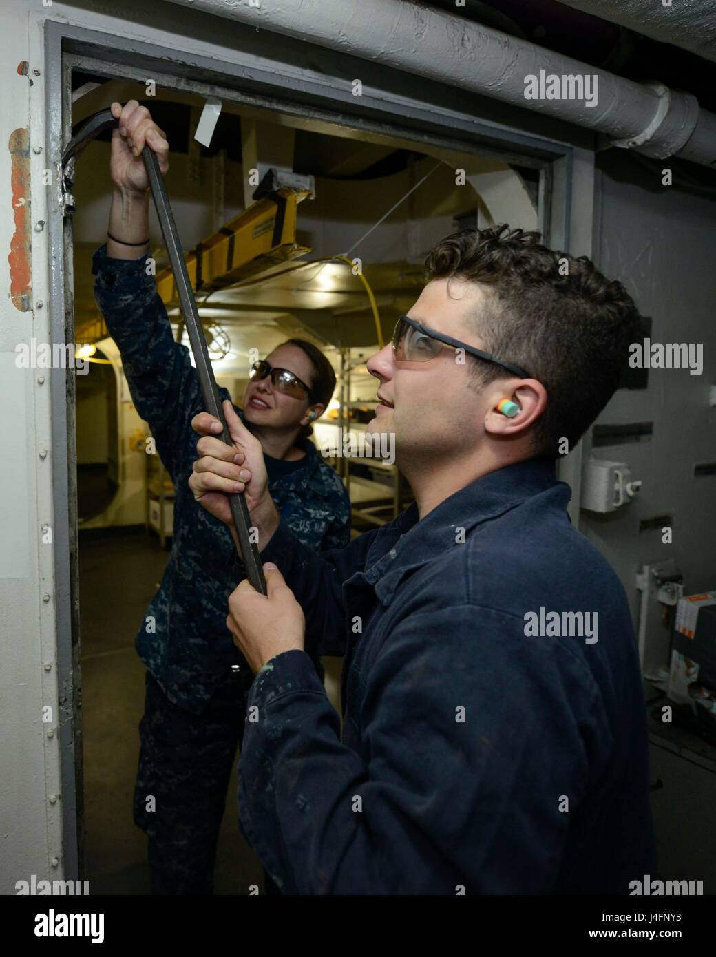 Il personale addetto alla manutenzione aeronautica esegue la manutenzione preventiva della USS Nimitz sostituendo una cerniera difettosa durante la disponibilità di manutenzione incrementale programmata estesa della nave presso il cantiere navale di Puget Sound. Foto Stock