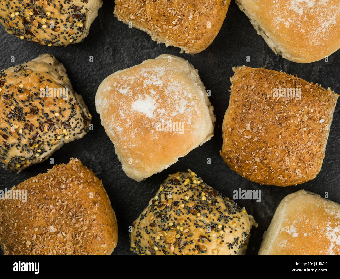 Selezione di pane misto rotoli o panini contro uno sfondo nero Foto Stock