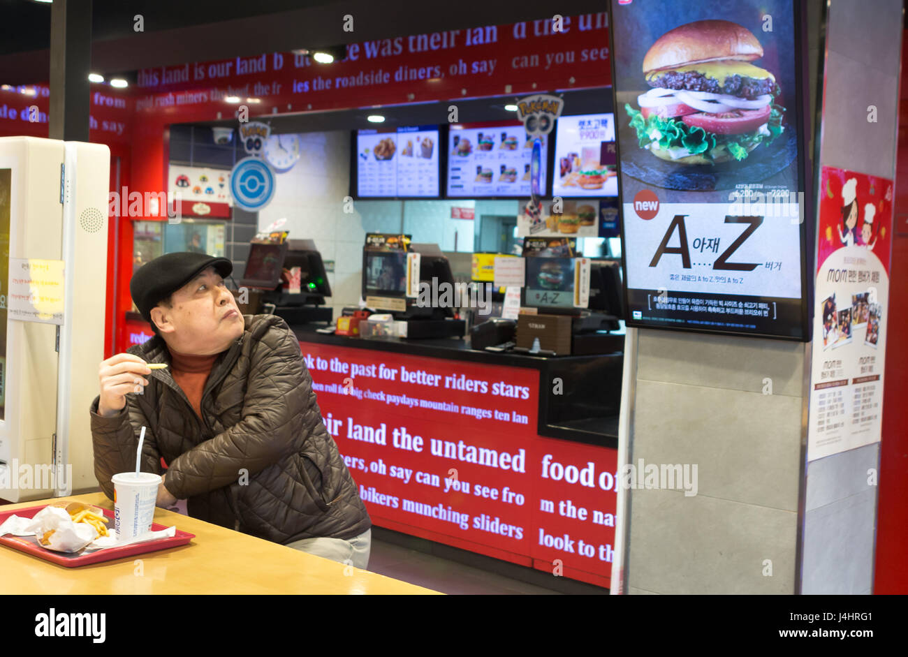 Busan, Corea del sud - marzo 27th, 2017: sud coreano uomo dentro un ristorante fast food cercando la hamburger pubblicità. Foto Stock