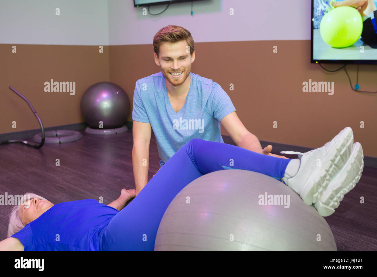 Fisioterapista pazienti guida gambe sulla sfera di aerobica Foto Stock