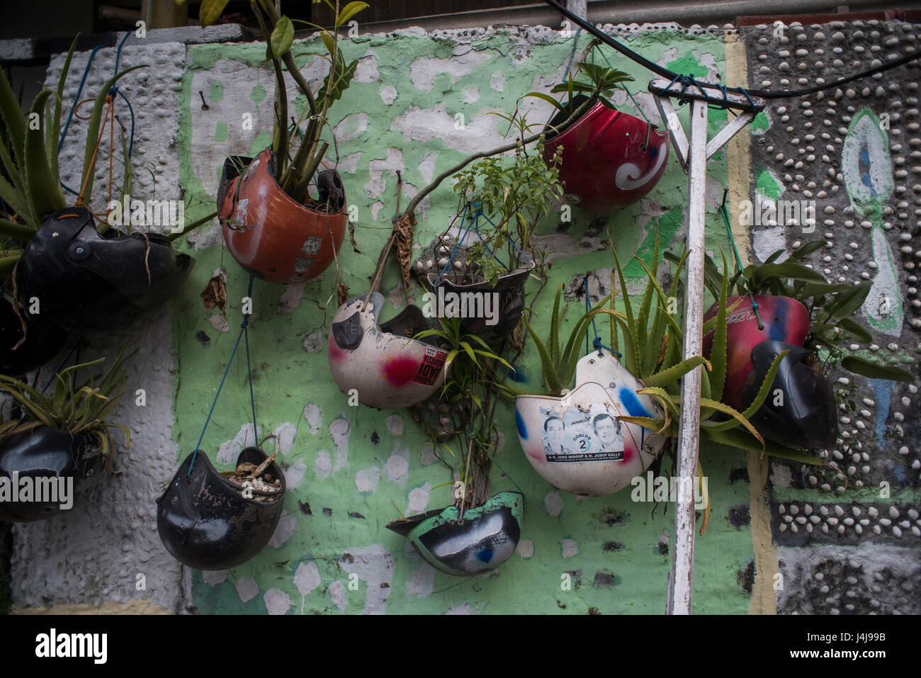 Caschi utilizzati come vasi per piante in una parete di Yogyakarta, Java, Indonesia. Foto Stock