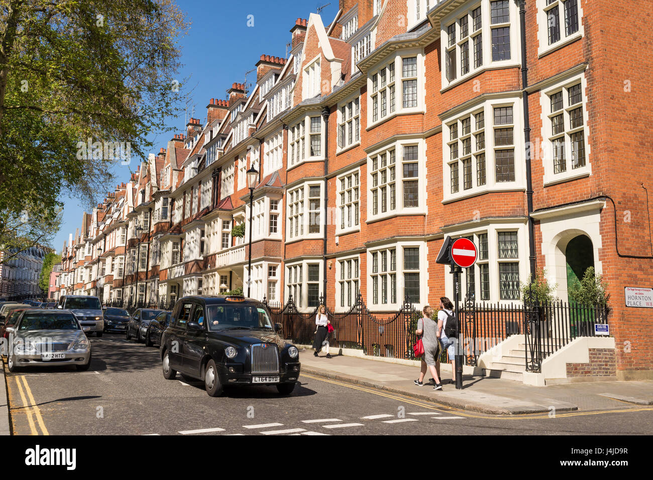 Vista della strada con gente che cammina, black cab e restaurato elegante Edwardian case di lusso in mattoni rossi nella esclusiva area di South Kensington Foto Stock