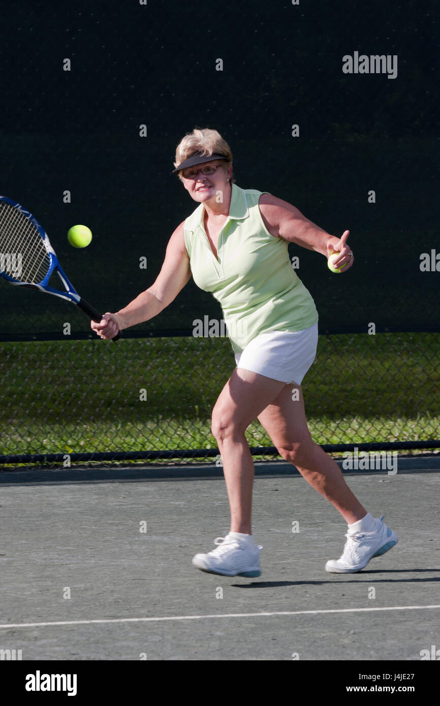 Senior donna giocatore di tennis circa per colpire un diretti shot Foto Stock