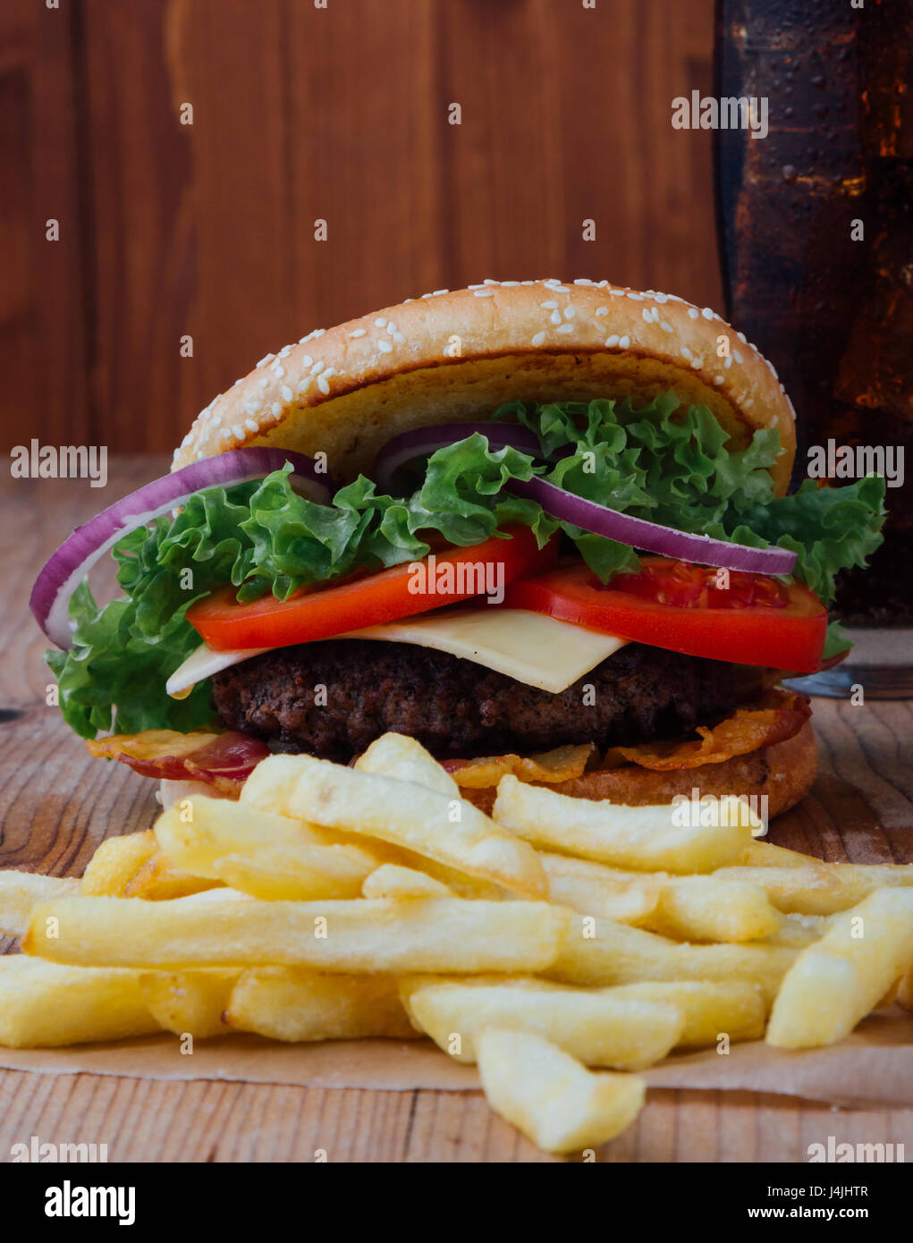 Hamburger con patatine fritte e bevanda fredda sul tavolo di legno Foto Stock