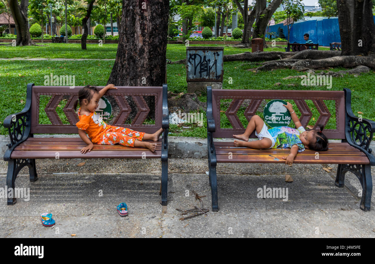 Due piccoli bambini che giocano sulle panchine in un parco a Saigon Vietnam Foto Stock