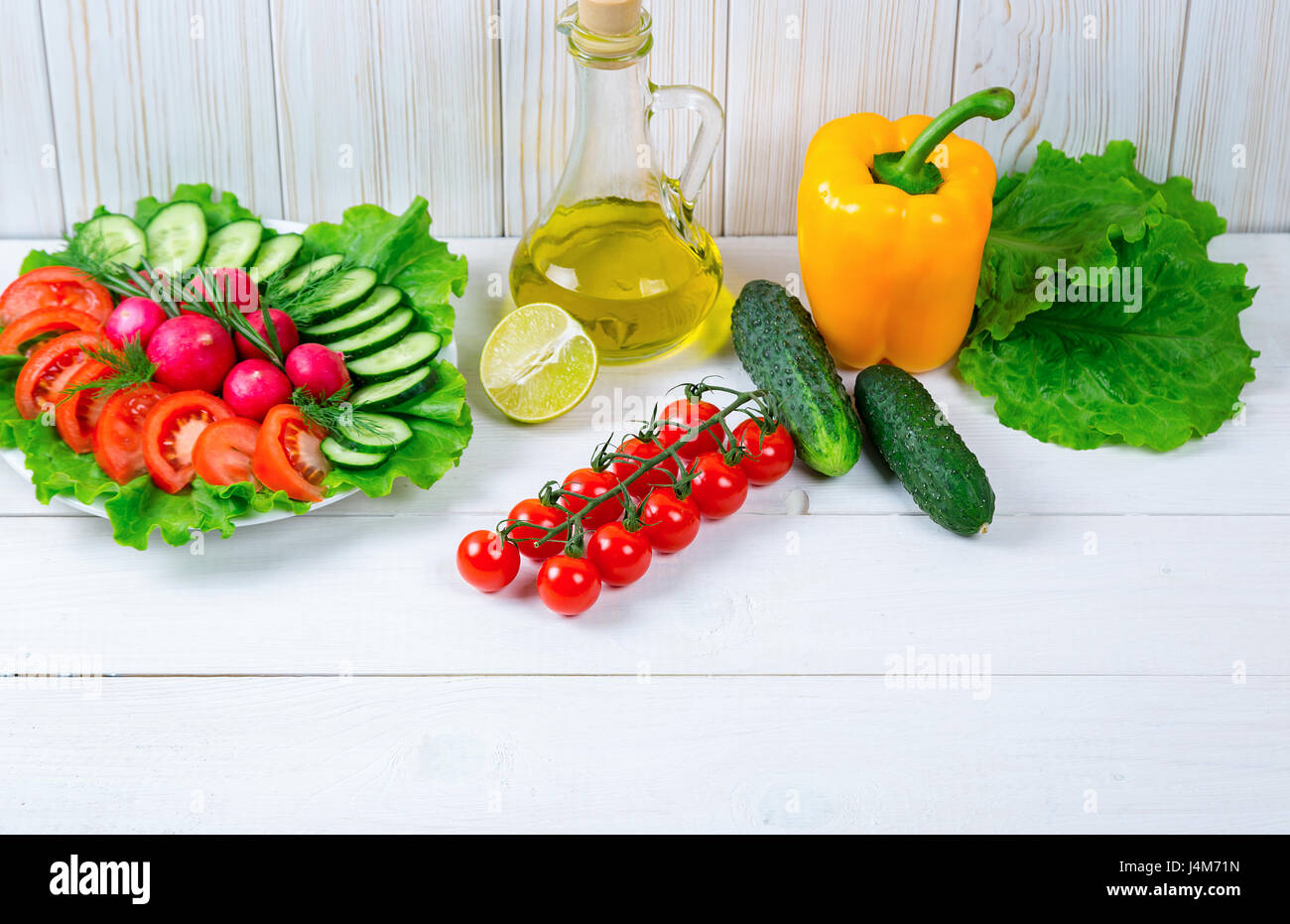 Cetrioli, Rafano, pomodori ciliegia, olio d'oliva, erbe e spezie sul vecchio bianco sullo sfondo di legno. Impostare i cibi sani. Ingredienti per insalata. Foto Stock