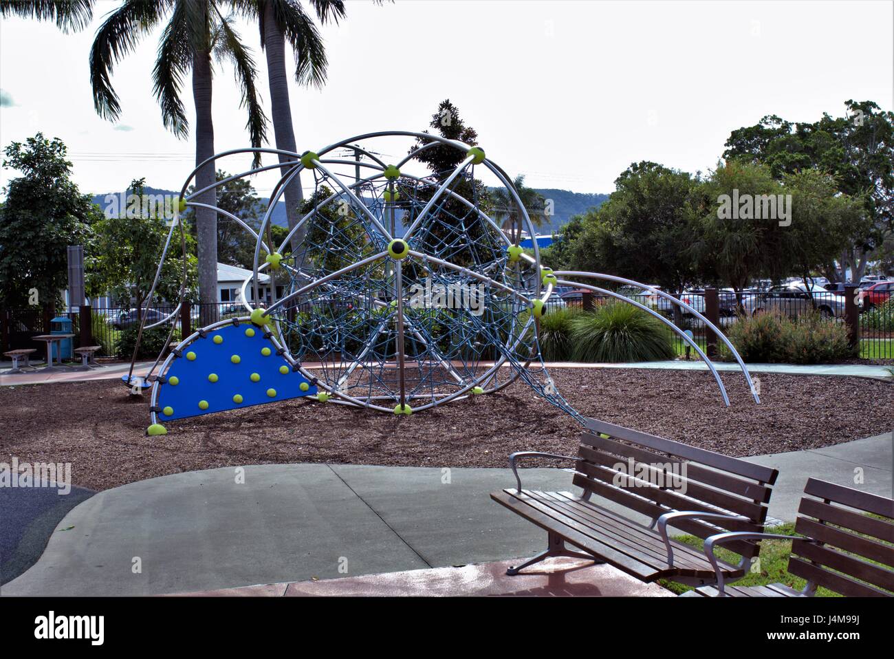 Parco per bambini in australiano. Parco per bambini con giostre realizzati in metallo e corde, erba, alberi e panchine in vista. Foto Stock