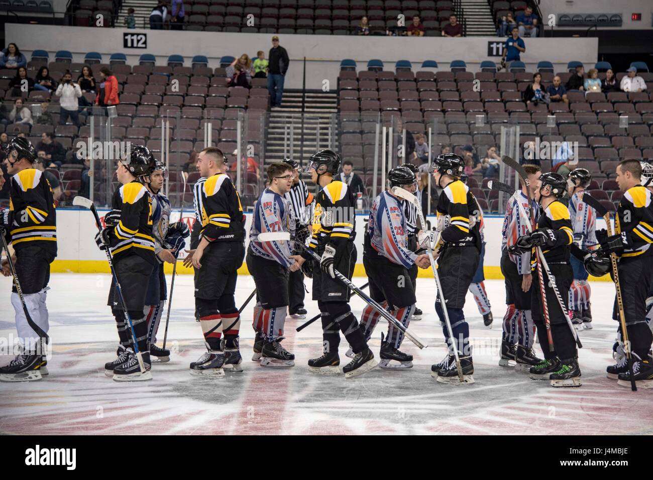 I marinai della USS Dwight D. Eisenhower e della USS Abraham Lincoln si salutano dopo una partita di hockey di beneficenza a sostegno della Navy-Marine Corps Relief Society alla Scope Arena, evidenziando il morale e l'impegno della comunità durante le operazioni di supporto. Foto Stock