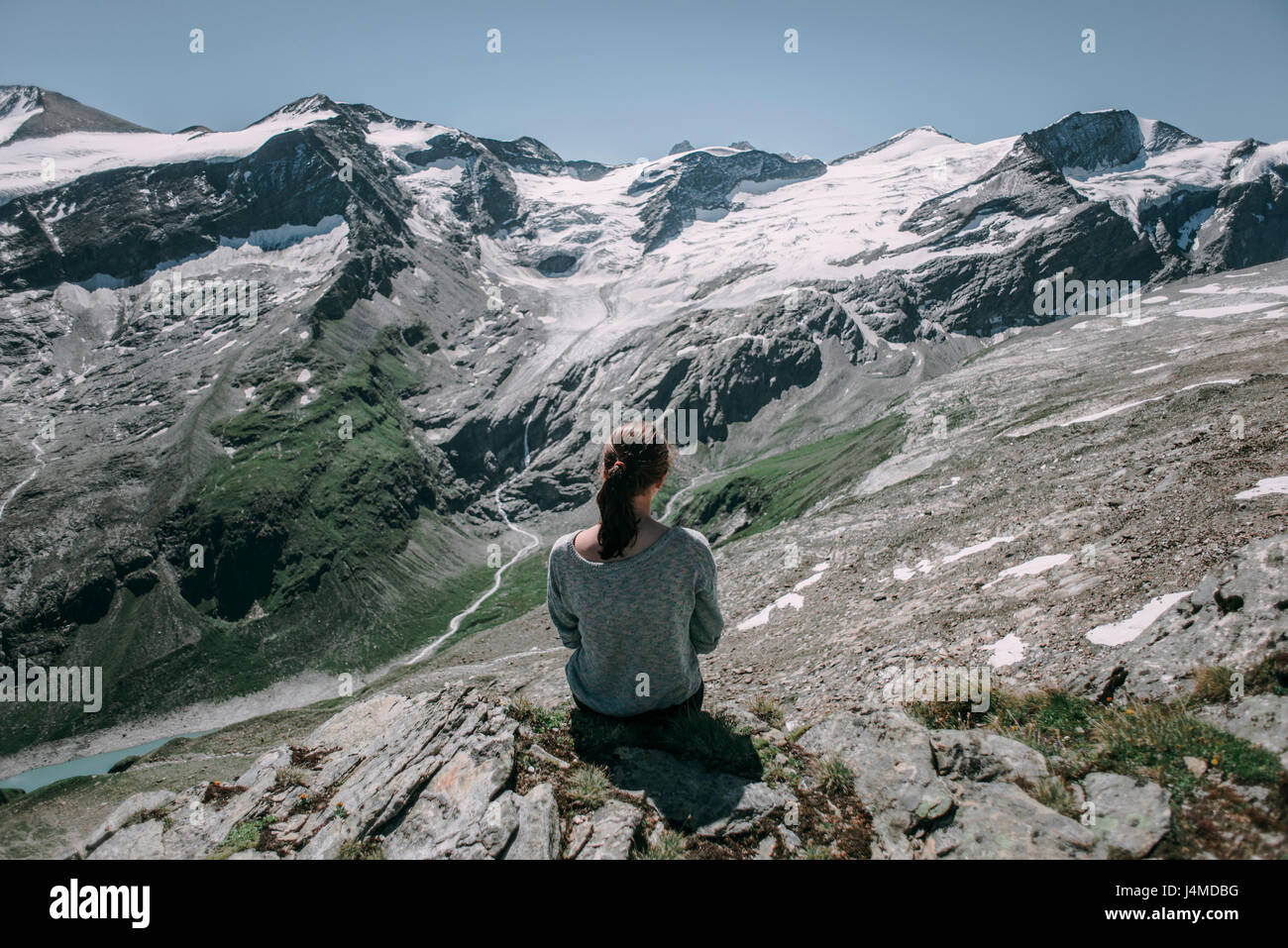 Caucasian donna seduta su roccia ammirando vista panoramica del monte Foto Stock