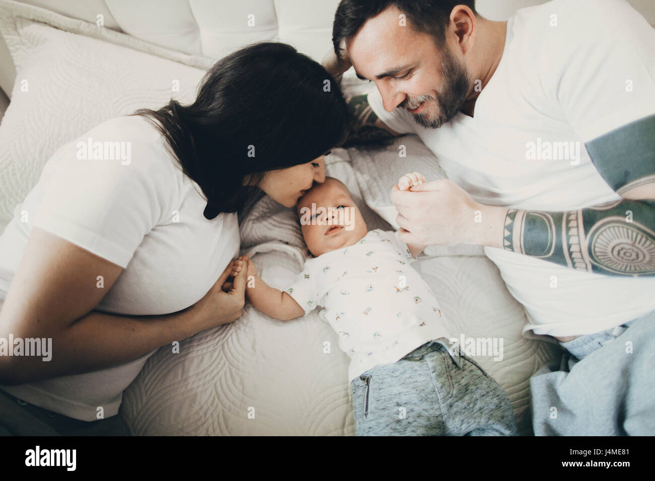 Caucasian il padre e la madre per mano con baby figlio sul letto Foto Stock