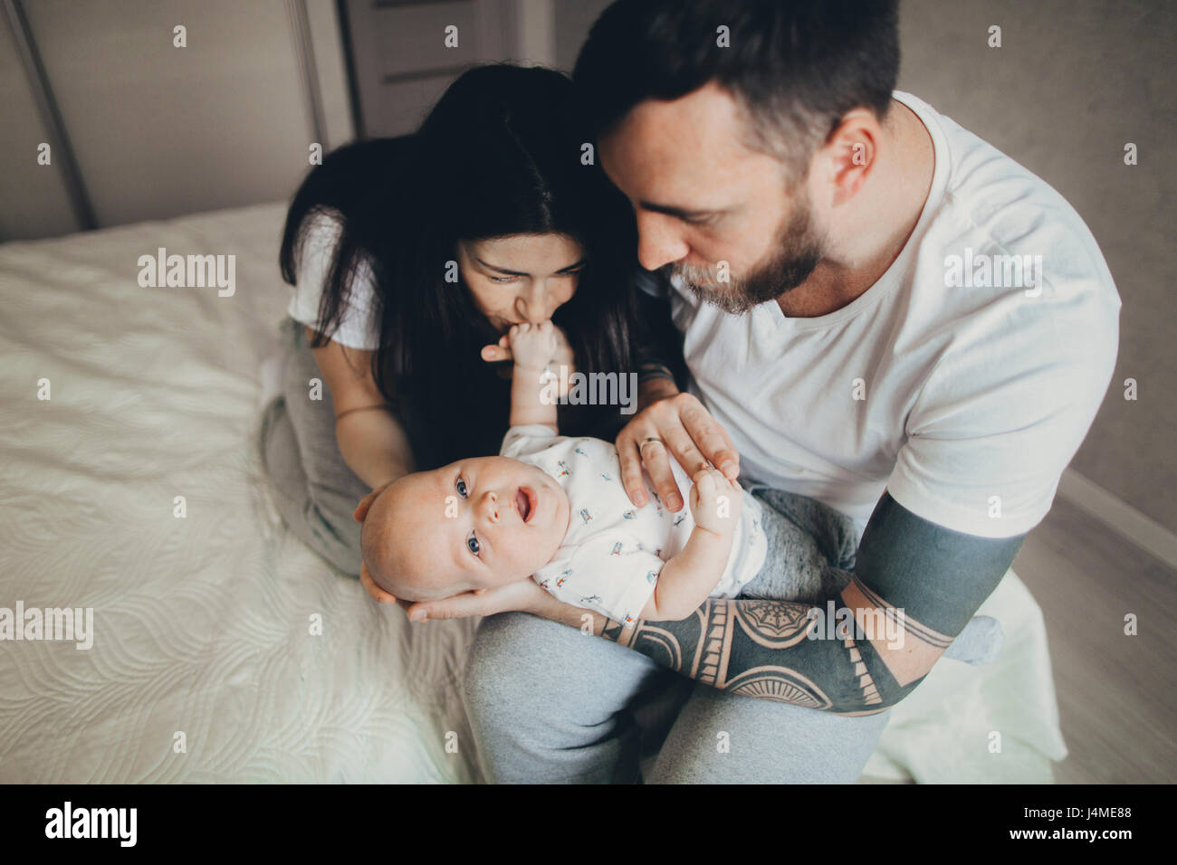 Caucasian madre e padre sul letto a giocare con il bambino figlio Foto Stock
