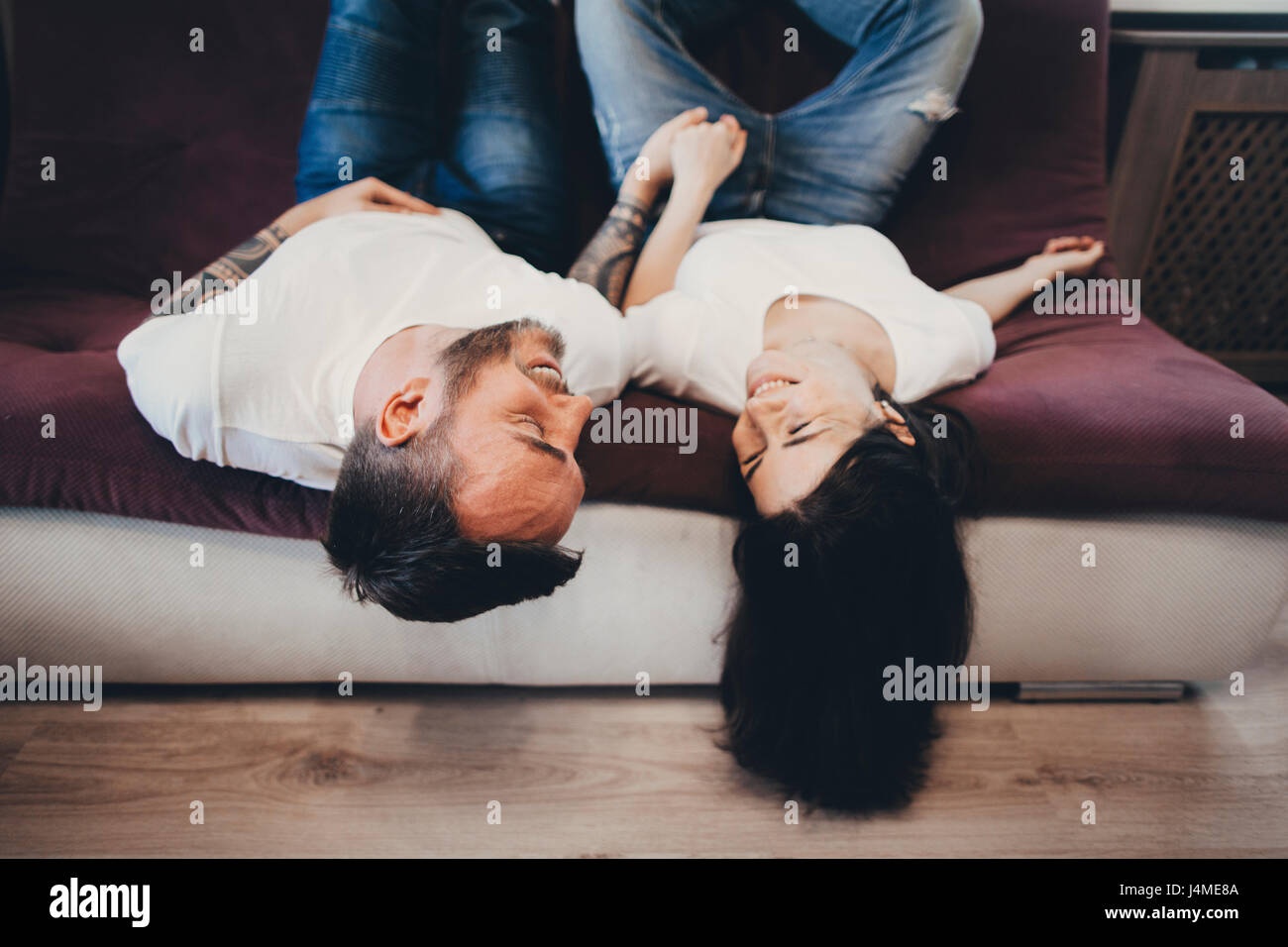 Coppia caucasica recante in posizione capovolta sul divano Foto Stock