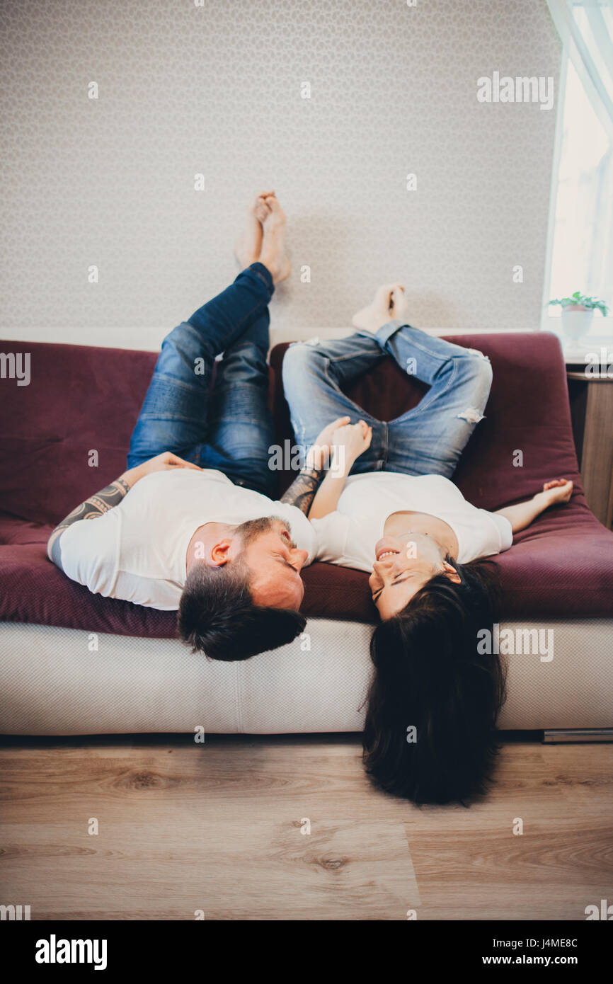 Coppia caucasica recante in posizione capovolta sul divano Foto Stock