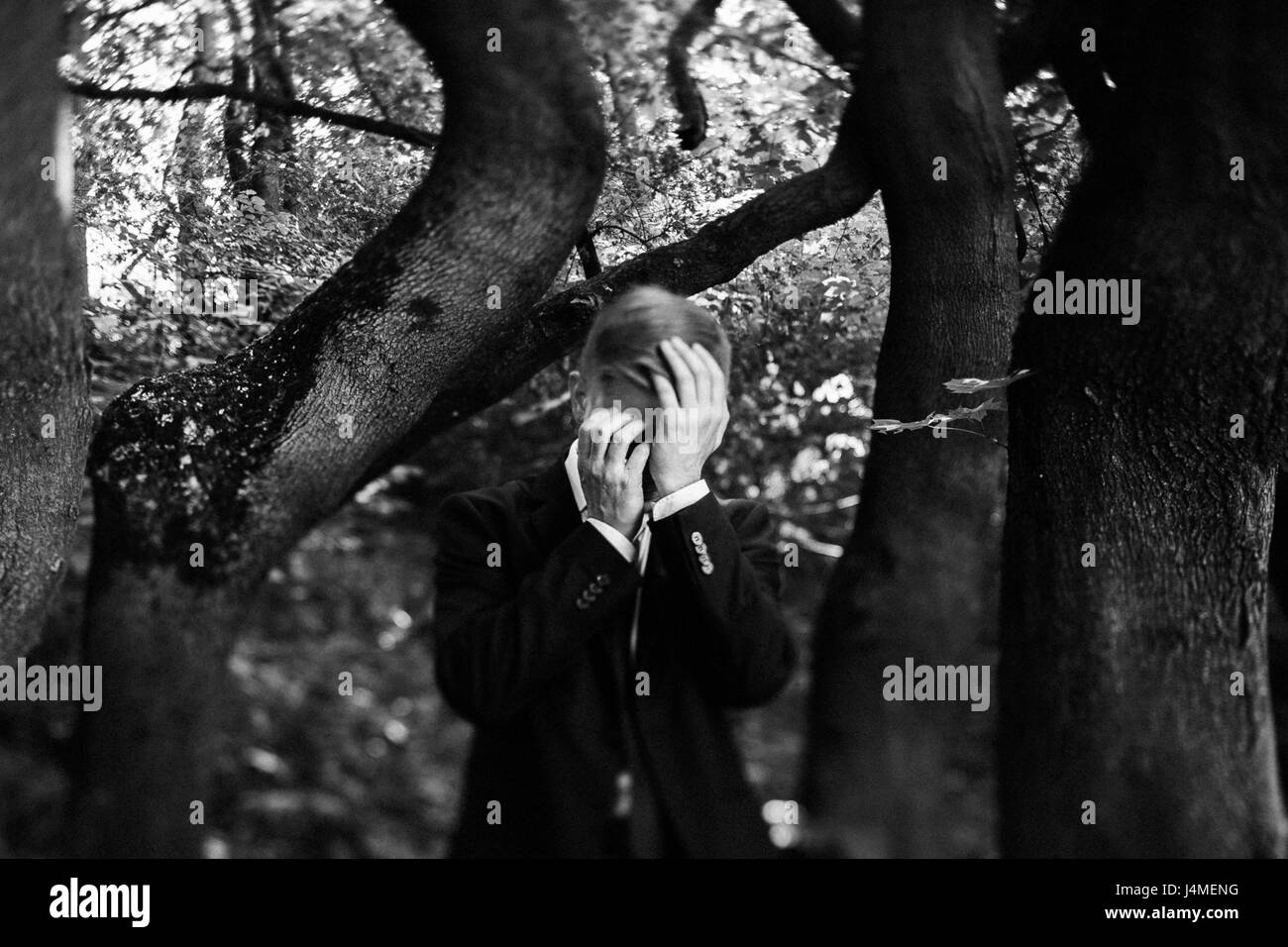 Imprenditore caucasico nella foresta con testa in mani Foto Stock