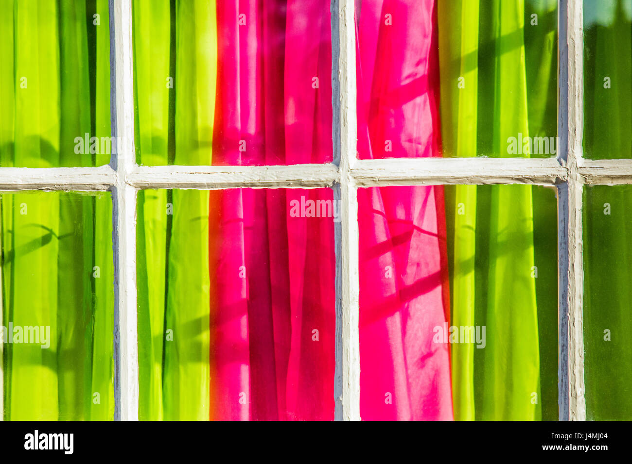 Colorato di rosa e verde tende visto dalla finestra esterna con riquadro francese Foto Stock