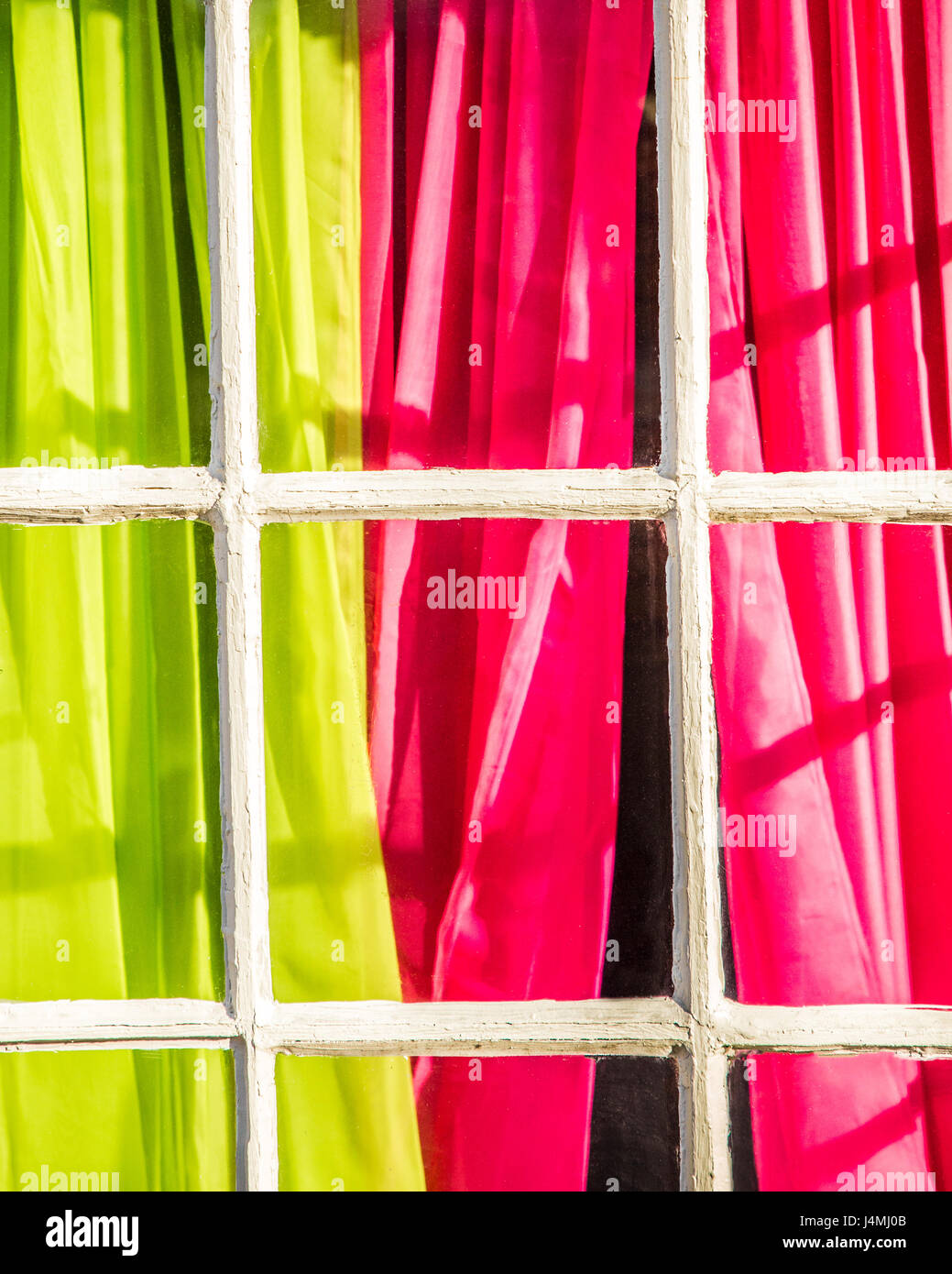 Colorato di rosa e verde tende visto dalla finestra esterna con riquadro francese Foto Stock