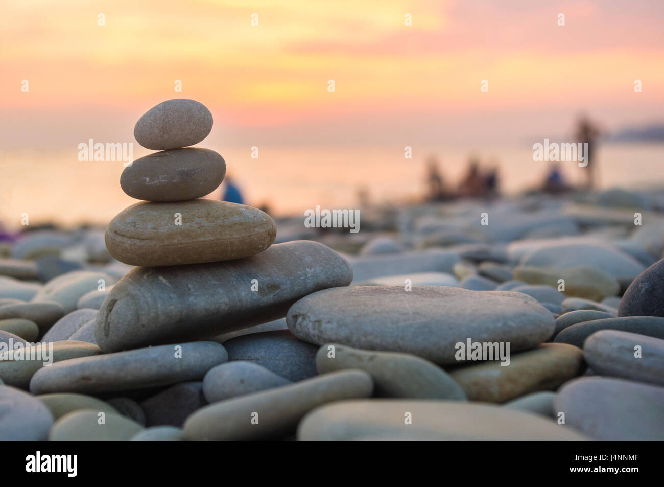 Piramide piegata Zen pietre ghiaia sul mare spiaggia al tramonto Foto Stock