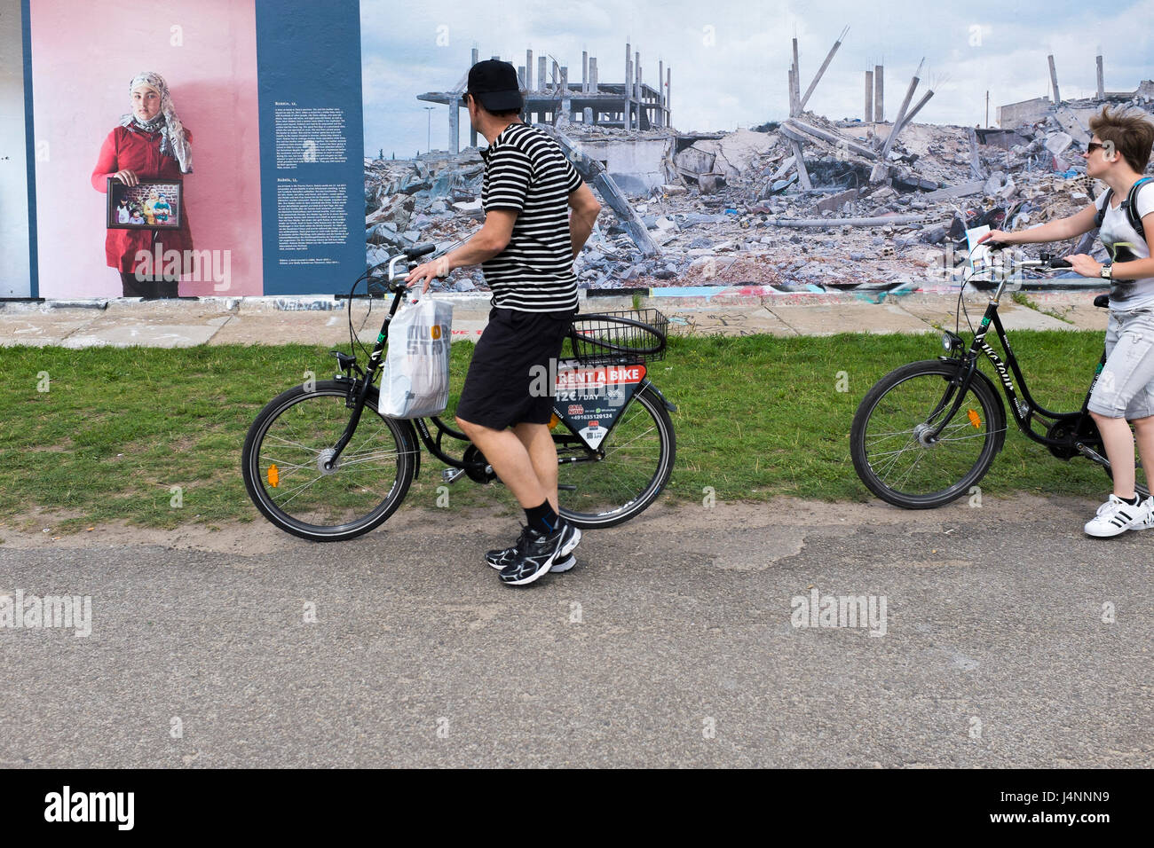 I berlinesi a piedi le loro biciclette passato una fotografia all'aperto gallery visualizzati sui resti del muro di Berlino nel regno città tedesca di Berlino Foto Stock