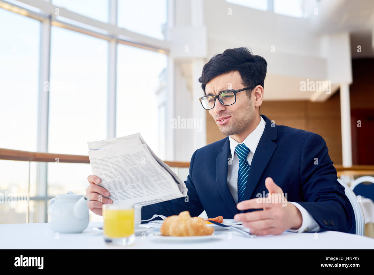 Giovane uomo seduto da tavola in cafe e la lettura delle news Foto Stock