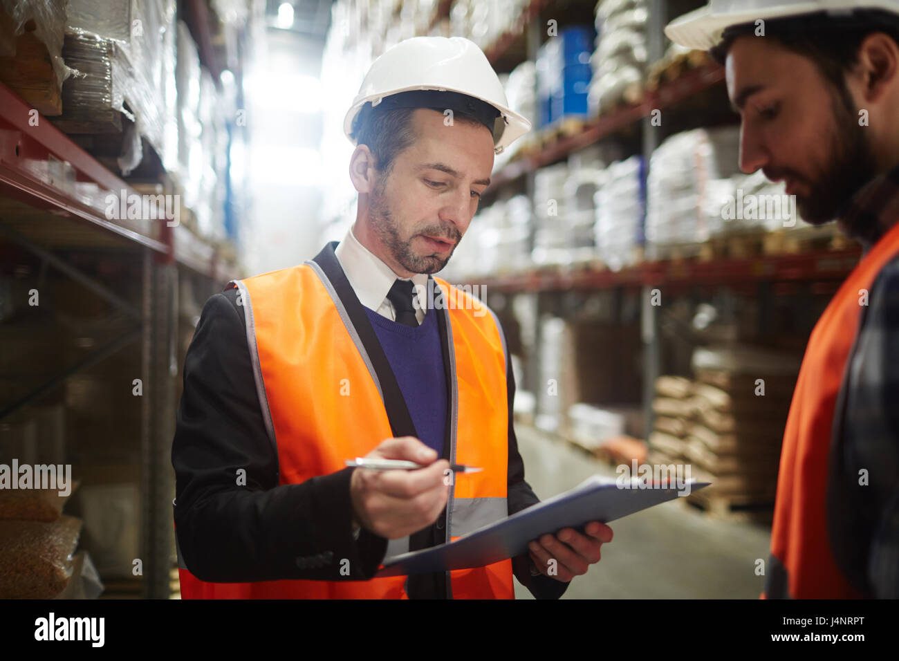 Lavoratore in casco e uniforme di Elenco lettura di merci spedite Foto Stock