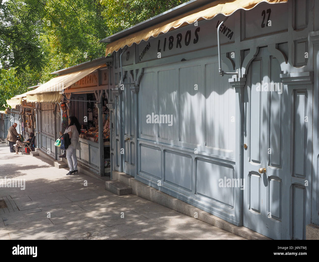 Una vista di shop bancarelle con tende da sole sul marciapiede marciapiede, guardando giù per la collina, alcuni imbarcati up chiusa per la siesta, su Calle de Alfonso XII, Madrid, Spagna Foto Stock