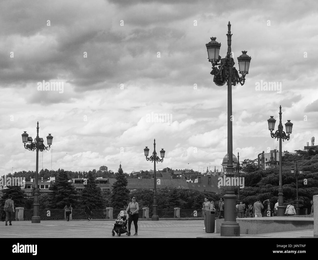 Un bianco e nero vista Street light luci lampade lamposts perforare il cielo nuvoloso il Jardines del Cabo Noval al di fuori del Palacio Real Foto Stock
