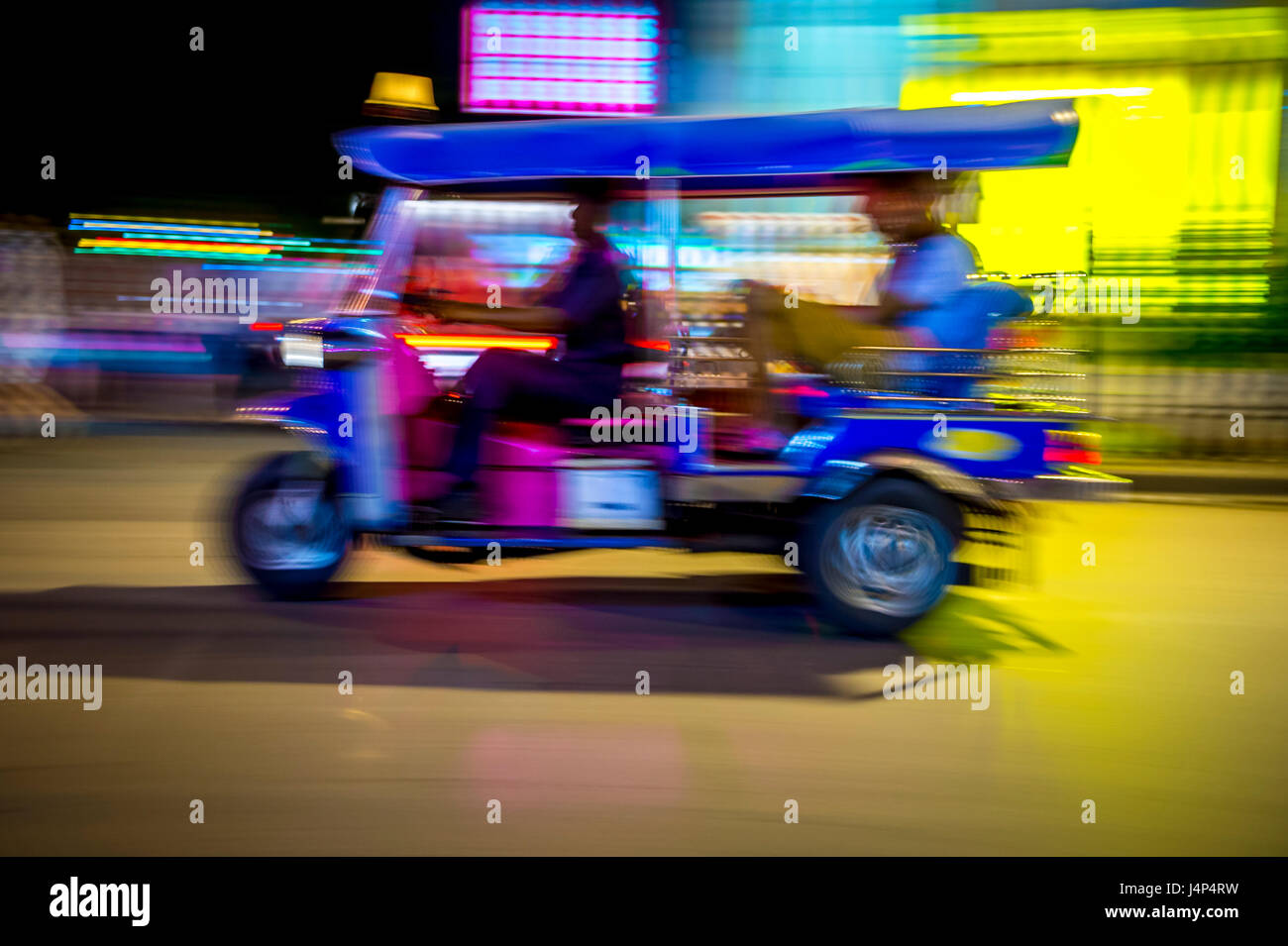 Un classico motorizzato di tuk-tuk taxi esegue lo zoom in una notte di sfocatura di luci al neon a Bangkok, in Thailandia Foto Stock