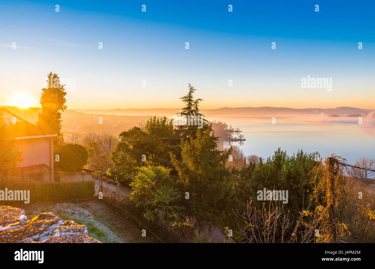 Spettacolare vista aerea di un lago all'alba. Il lago di Varese, Italia. A destra, nella nebbia, puoi vedere la piccola isola Virginia a Biandronno, provincia di Foto Stock