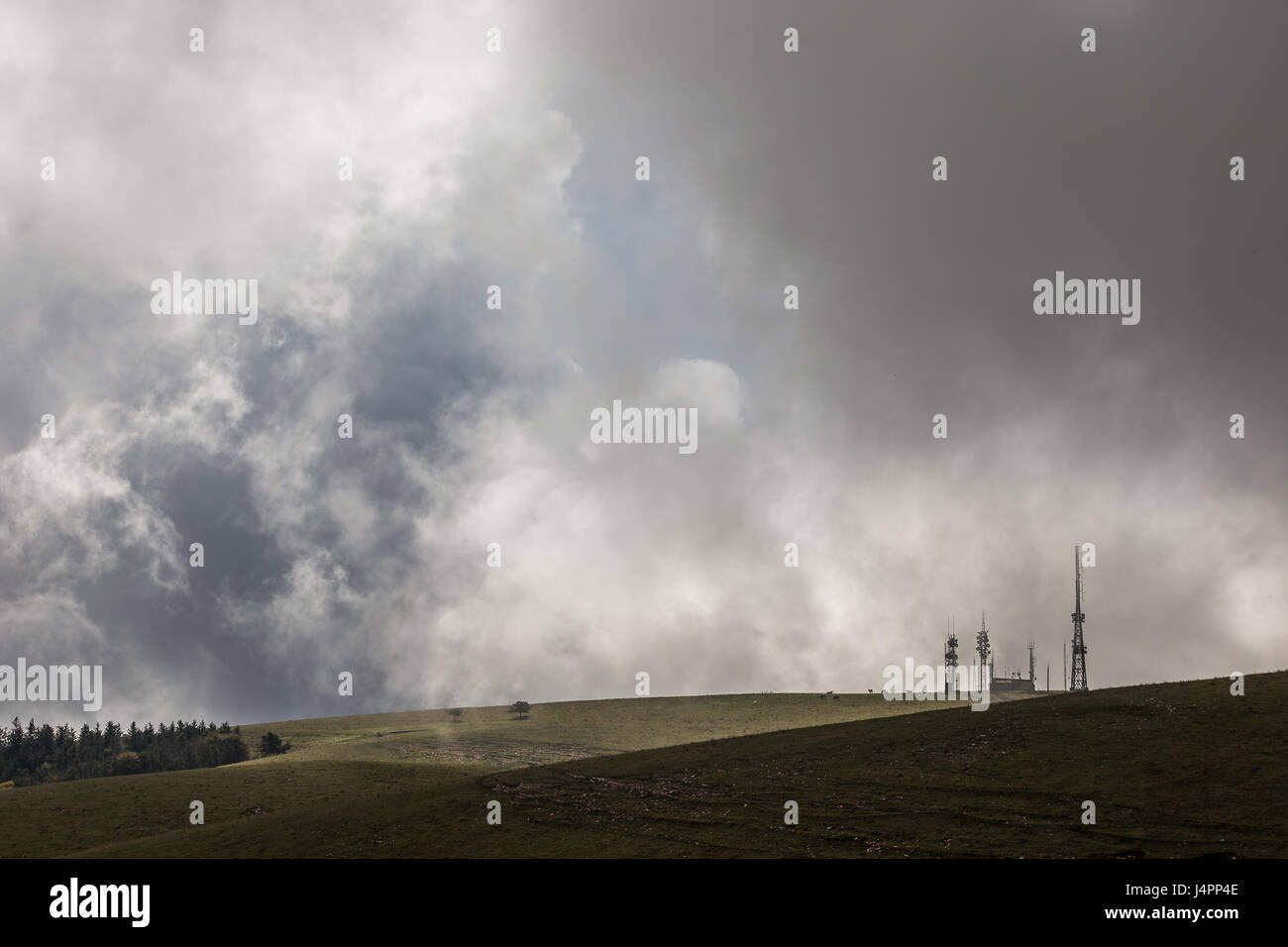 Alcune antenne sulla cima di una montagna con una parete di nuvole e nebbia Foto Stock