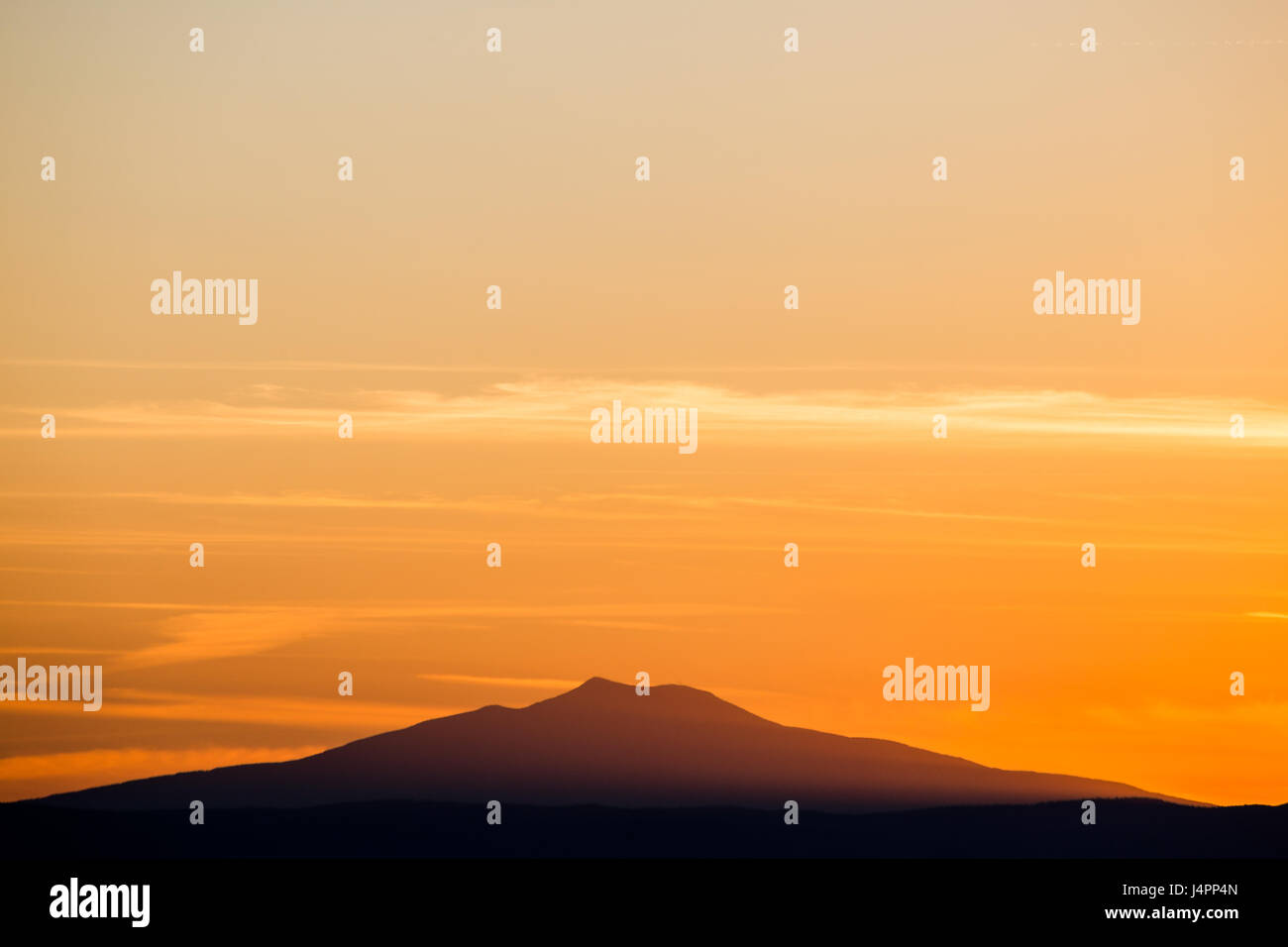 Un molto essenziale riprese di una montagna al tramonto, con bellissime red sky e qualche piccolo e lungo le nuvole piene di luce. Foto Stock