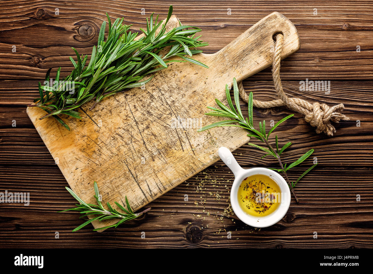 Sfondo culinario con tavola di legno e cottura ingredienti, olio di oliva e rosmarino, sopra visualizza lo spazio per un testo Foto Stock