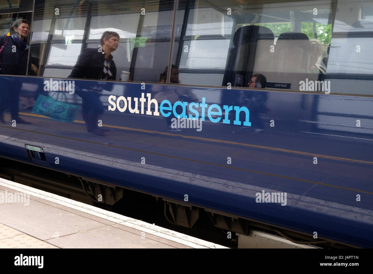 Treno sud-orientale che aspetta alla stazione internazionale di Ashford, riflessione passeggeri, persone, logo sul treno, ashford, kent, regno unito Foto Stock