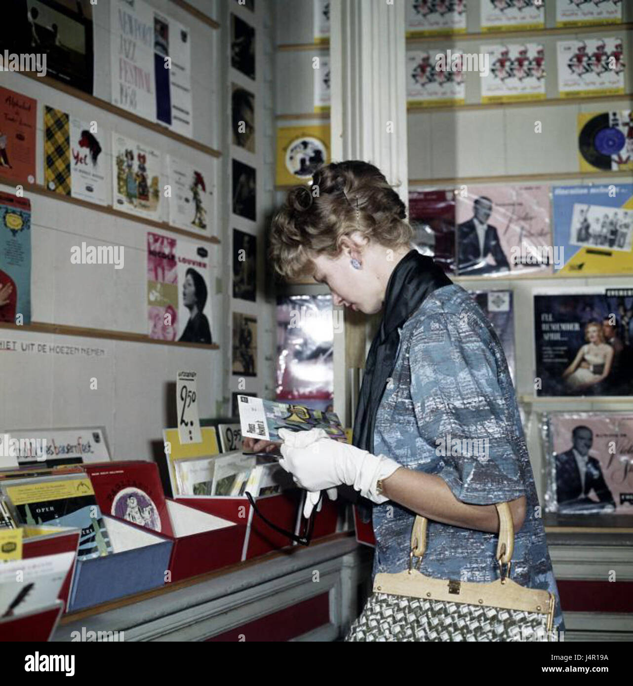 L'immagine raffigura una donna che naviga attraverso un negozio di dischi, un ambiente che mette in evidenza il significato della musica nella cultura. I negozi di dischi sono stati a lungo centri culturali per gli appassionati di musica, offrendo un'ampia gamma di generi musicali e dischi in vinile. Foto Stock