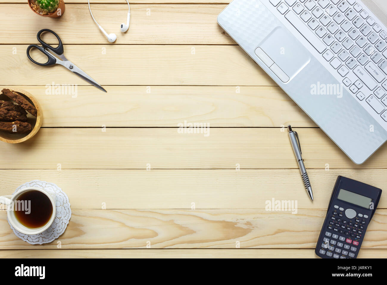 Vista superiore laptop ,penna,nero caffè,calcolatrice,fermo,auricolari, cookie sulla scrivania in ufficio lo sfondo. Foto Stock