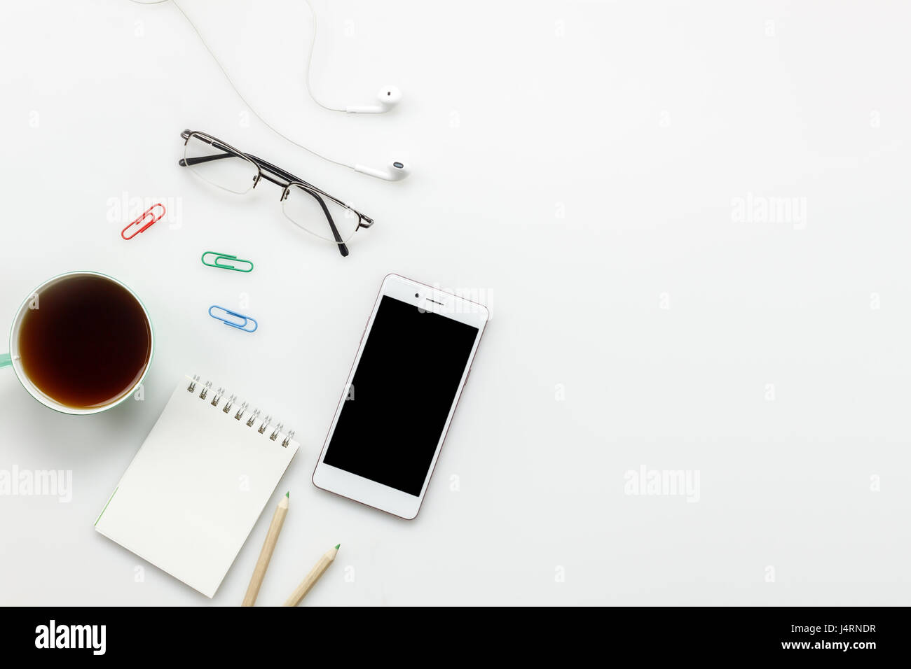 Top Visualizza accessori ufficio concetto.telefono mobile,caffè,notepaper,matita,auricolari sulla scrivania in ufficio. Foto Stock