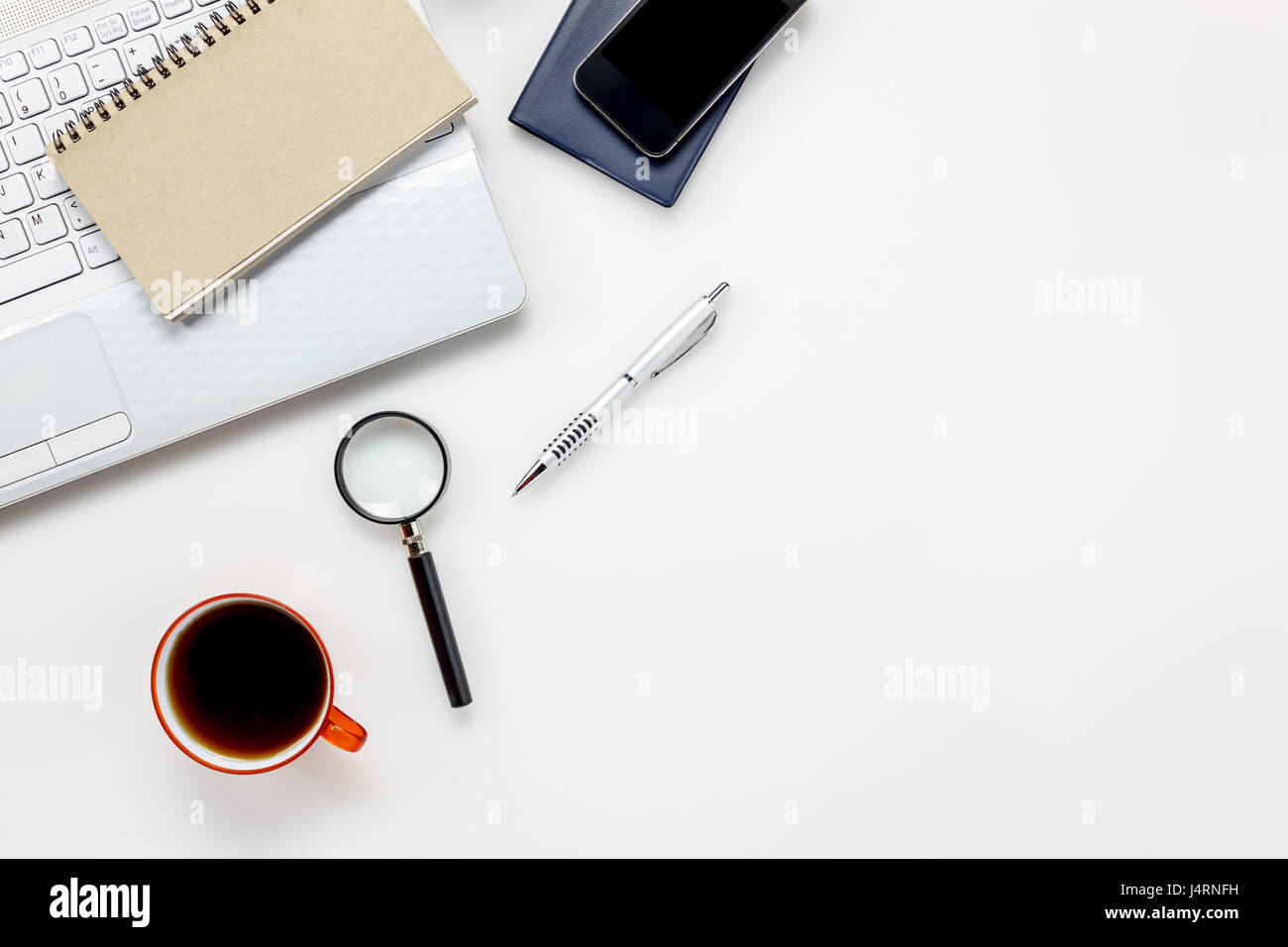 Top Visualizza accessori ufficio concetto.telefono mobile,notepaper,pen,laptop,Magnifier bianco sulla scrivania in ufficio. Foto Stock