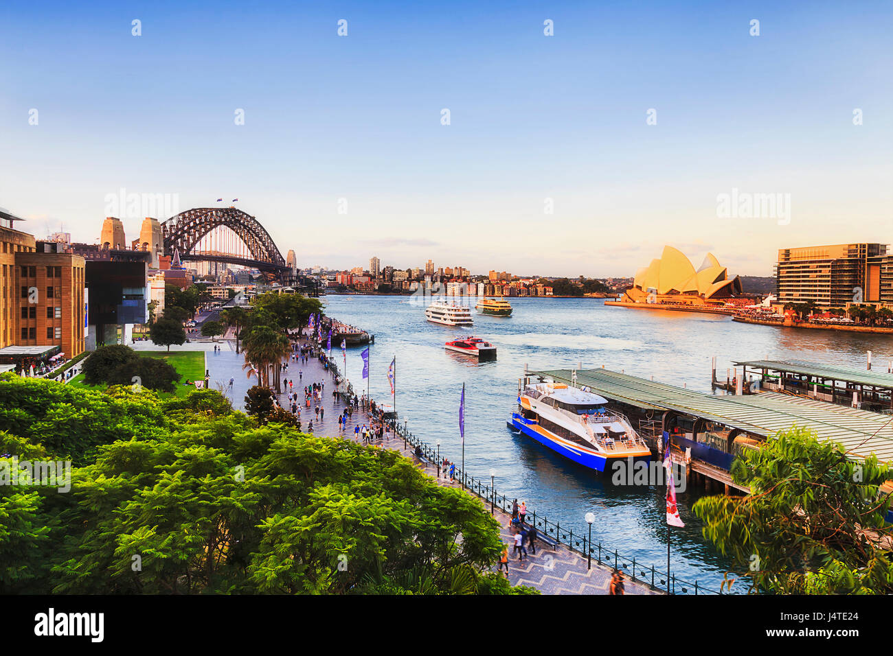 Il Circular Quay locale e all'estero porto per i traghetti e l'oceano crociera in caldi sunsetting luce verso il porto di Sydney e Harbour Bridge. Foto Stock