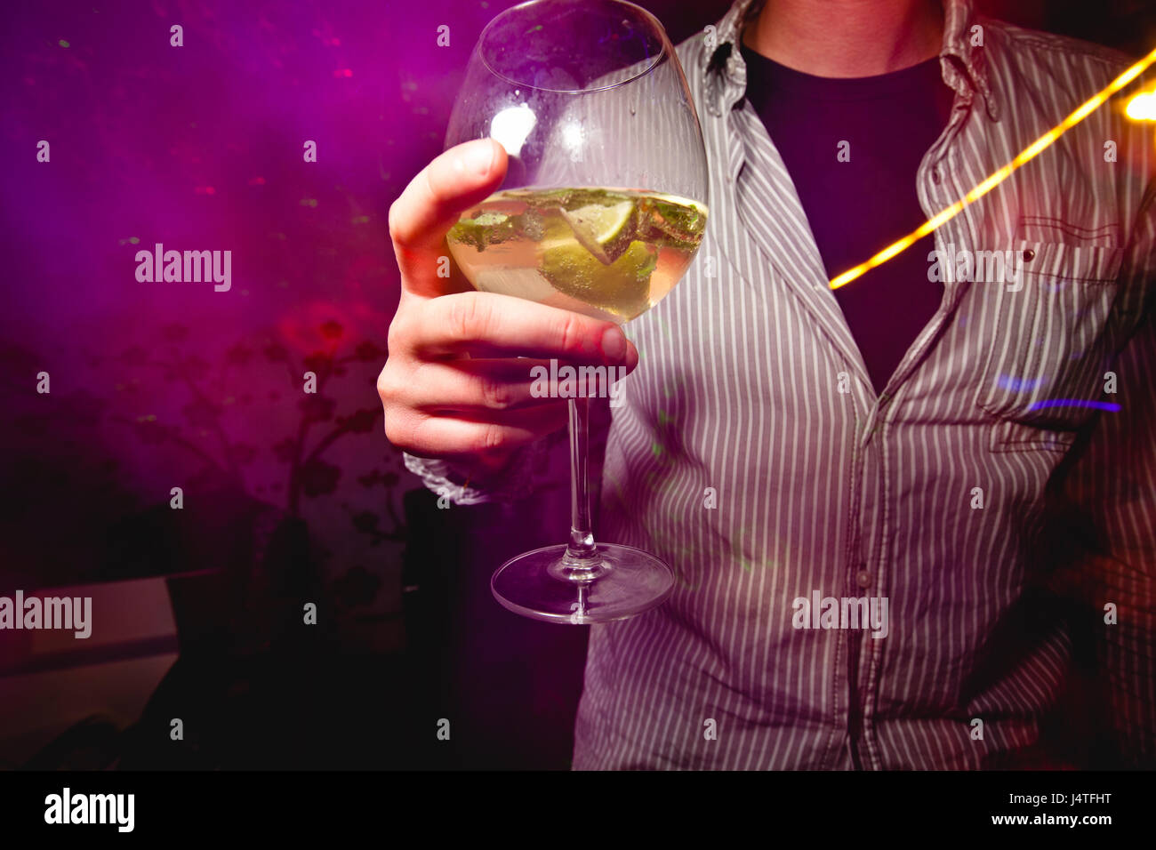 Uomo caucasico holding bicchiere da cocktail nelle sue mani in un night club Foto Stock