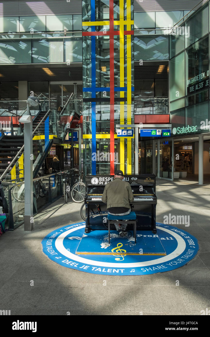 Uomo a suonare il piano all'interno della stazione centrale, l'Aia, Olanda, Paesi Bassi. Foto Stock