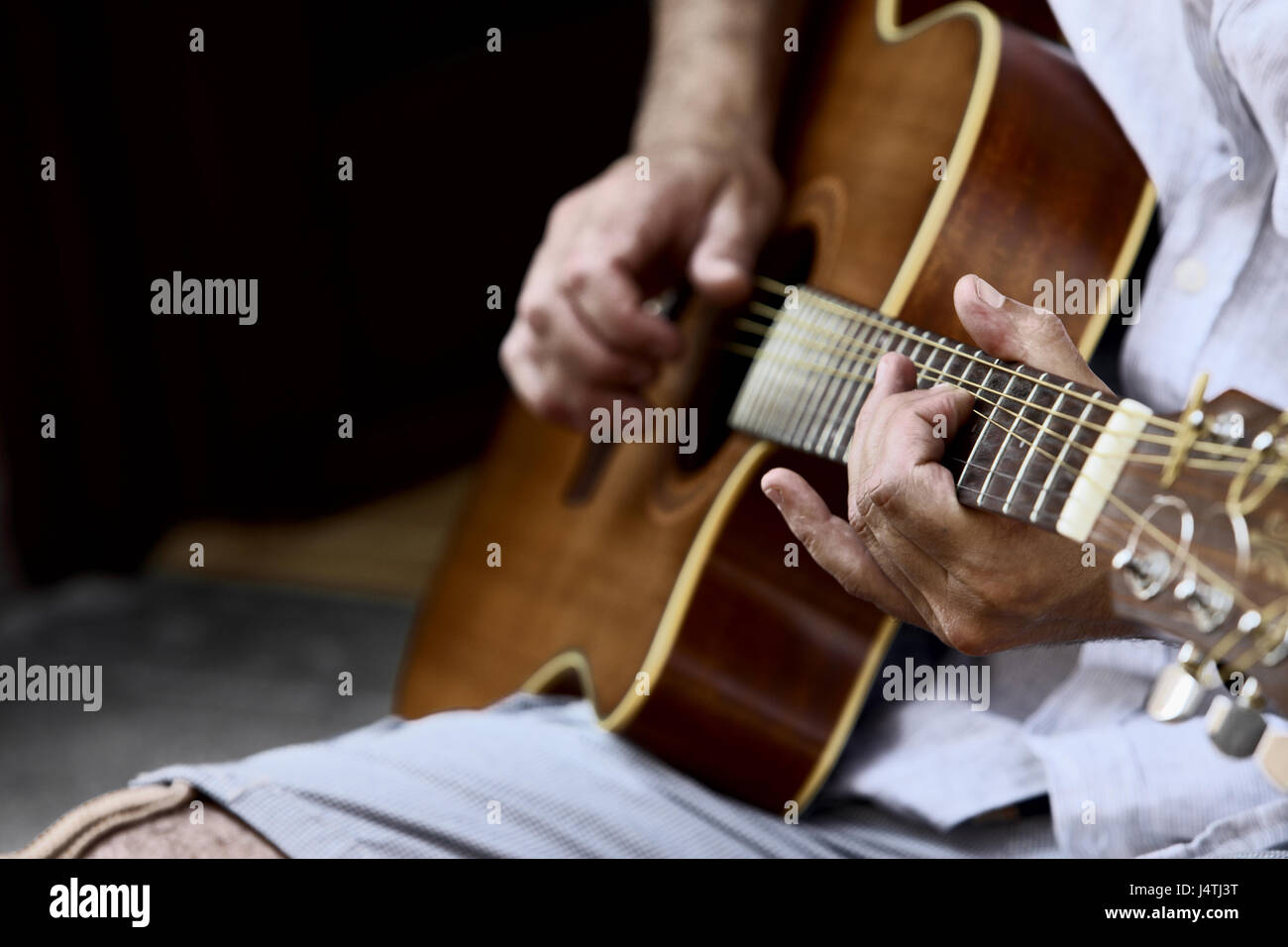 Primo piano della chitarra acustica e del musicista mani, basse profondità di campo Foto Stock