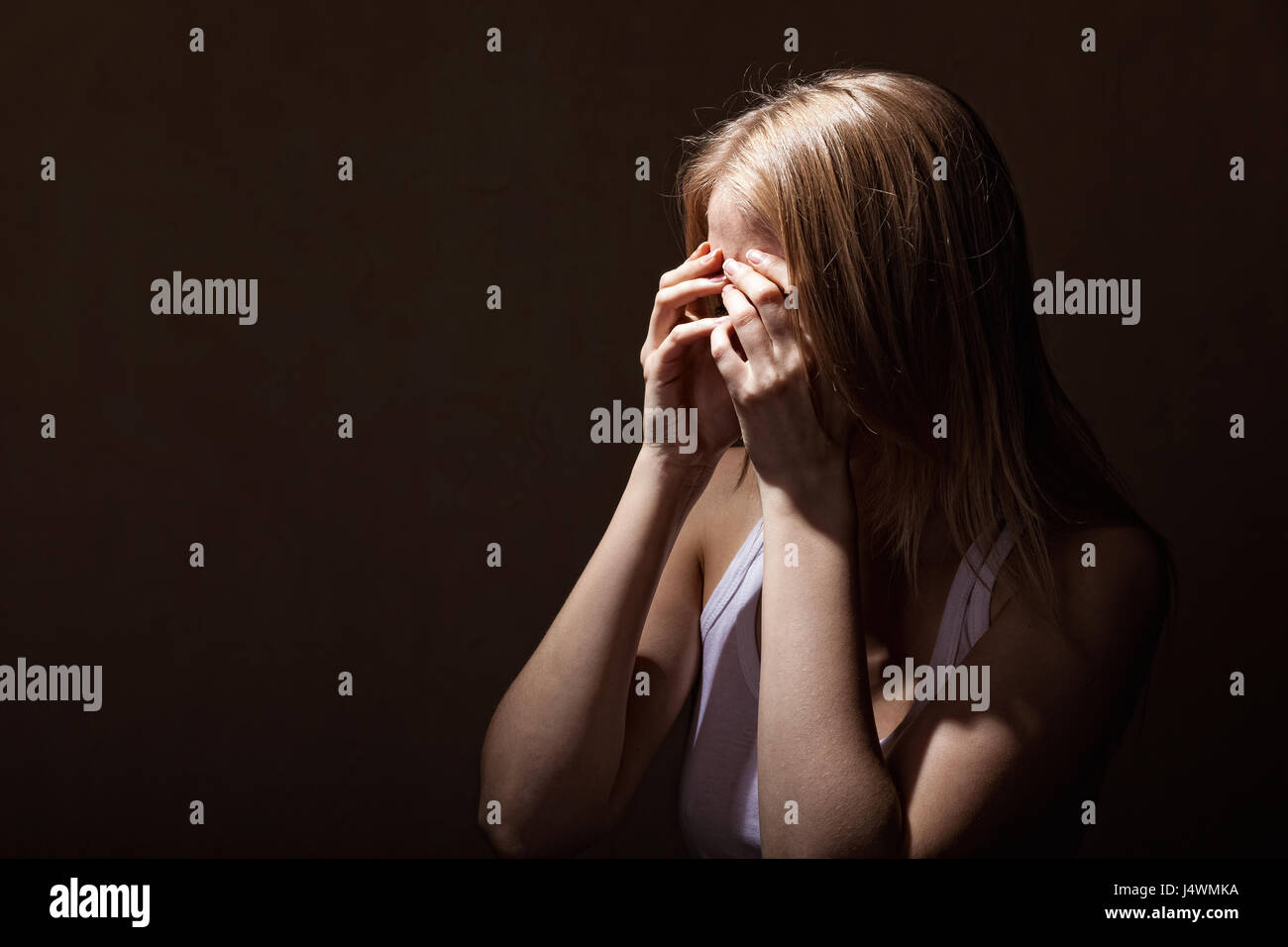 Giovane donna di pianto su sfondo scuro Foto Stock