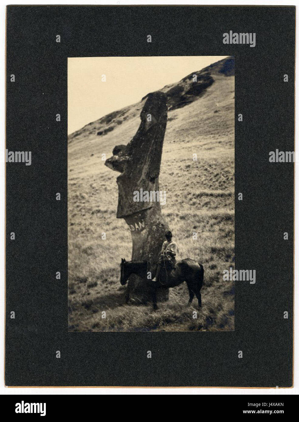 Vista di un moai (pietra figura carving) metà visibile; un ragazzo su un cavallo che è seduto di fronte alla figura; quattro lettere bianche visibili sul collo della figura; fotografato su pendii di Rano Raraku, Oc,B30.8, Mana spedizione in 0004 Foto Stock