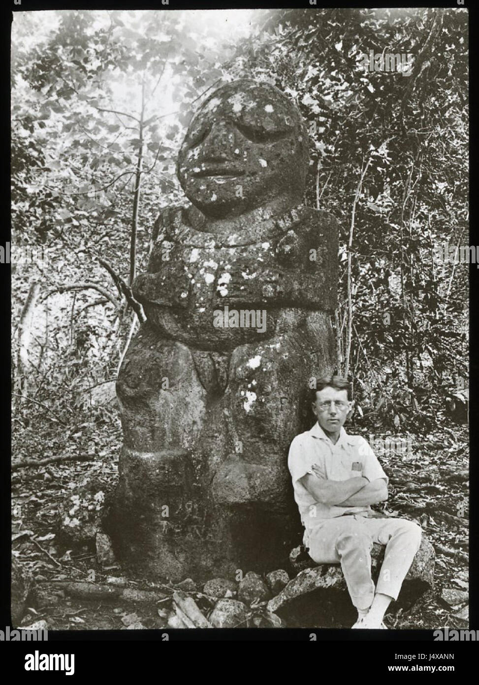 Vista di una pietra figura antropomorfa statua, circondato da alberi e fauna e con un uomo bianco seduto accanto a esso, per la scala; Raivavae, Polinesia. Oc,G.T.1672, Mana spedizione in Oriente Polinesia, British Museum Foto Stock
