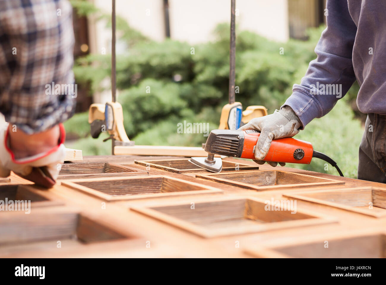 Carpenter al lavoro con la smerigliatrice angolare. La manutenzione e il restauro di una vecchia porta di legno. Foto Stock