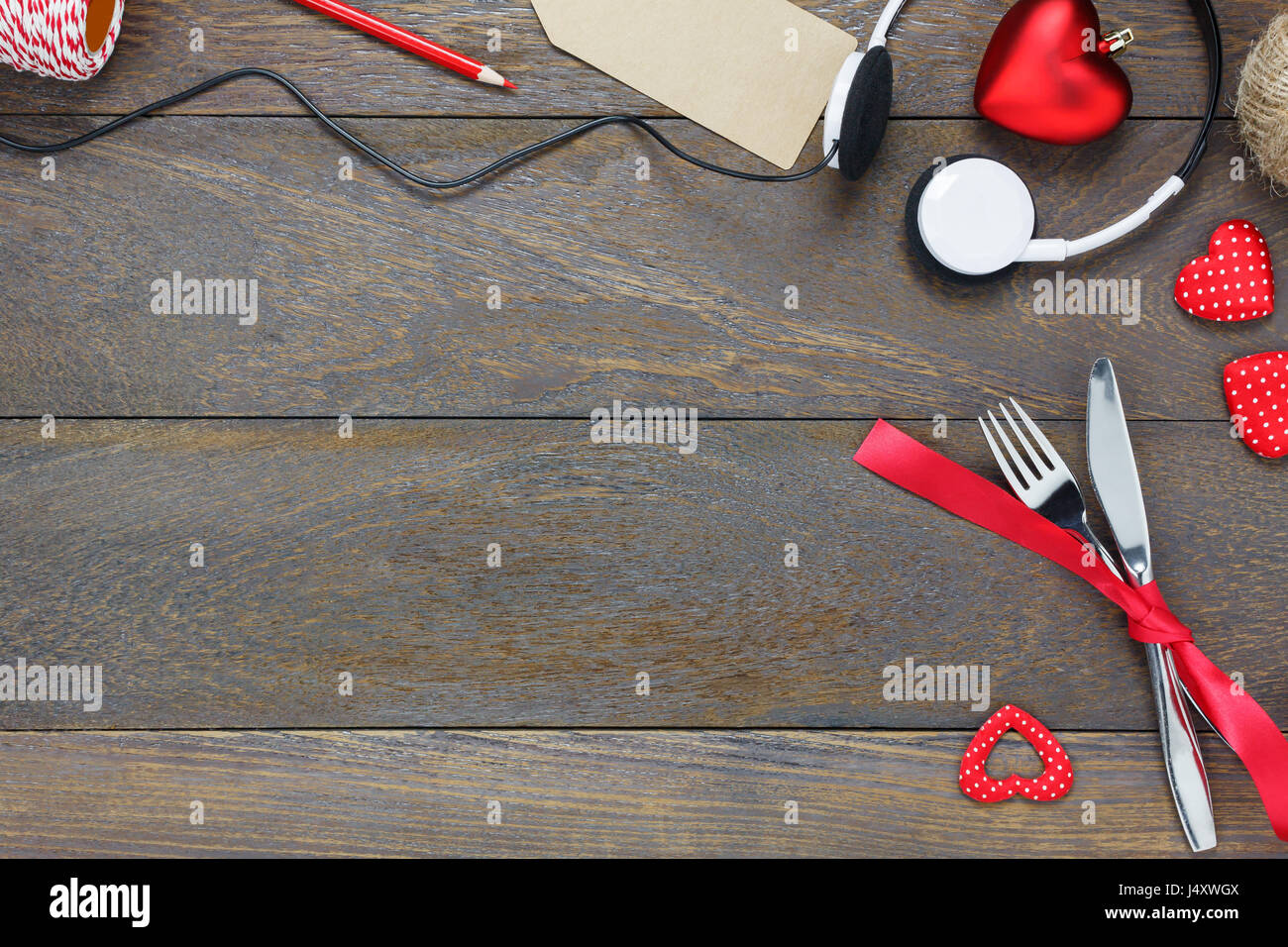 Vista dall'alto il giorno di San Valentino e musica di sottofondo.Cena e amo la musica coltello forcella nastro rosso cuffie e forma di cuore in legno con copia spazio. Foto Stock