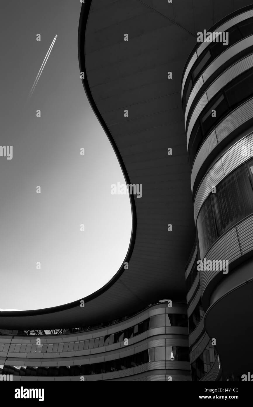 Un tetto curvo di un edificio la traccia di un s, con sky sul background e un irplane contrail Foto Stock