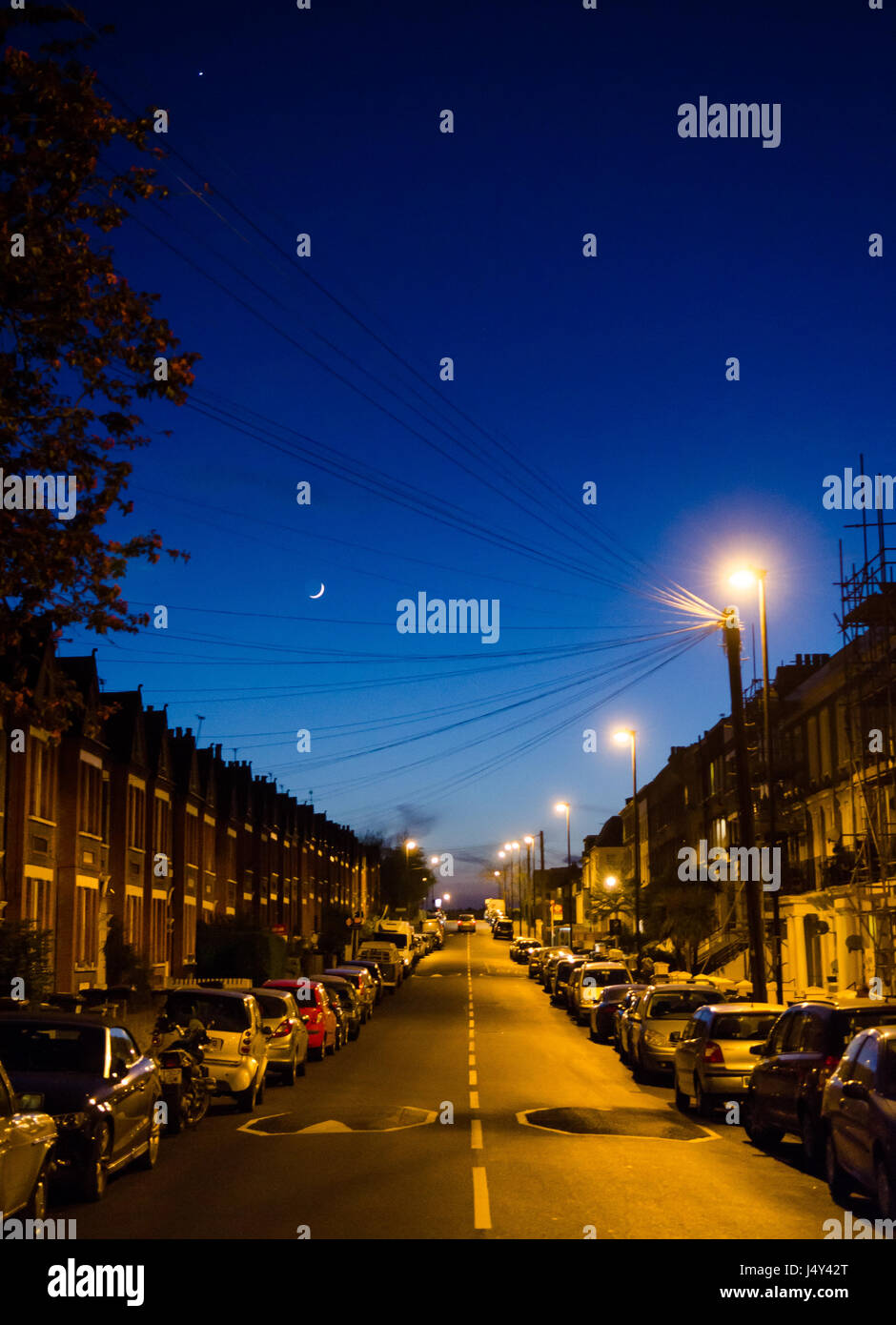 London, England, Regno Unito - 20 Aprile 2015: La luna sorge sopra suburbana di tradizionali case a schiera e le macchine parcheggiate nel Gipsy Hill quartiere di Sou Foto Stock